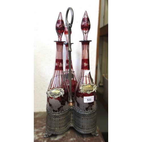 522 - Bohemian red flash glass three bottle decanter set with plated labels and stand, 47cm high