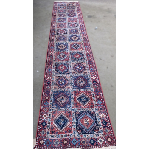 18 - Indo-Persian runner with a repeating hooked medallion design in shades of red and blue, 397 x 82cm