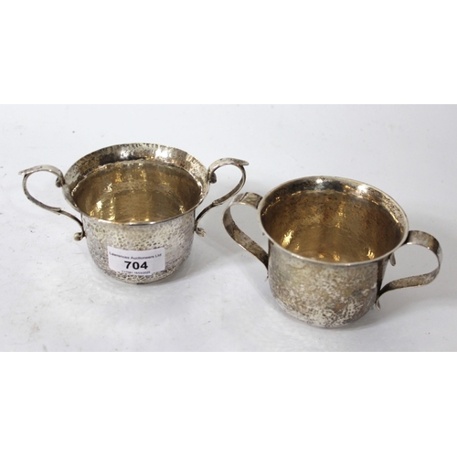 704 - Pair of early 20th Century hand beaten silver two handled porringers, London 1919, maker Goldsmiths ... 