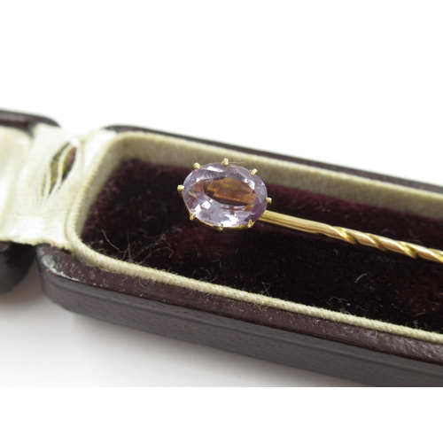 734 - 19th Century gold stick pin, mounted with an oval mauve sapphire