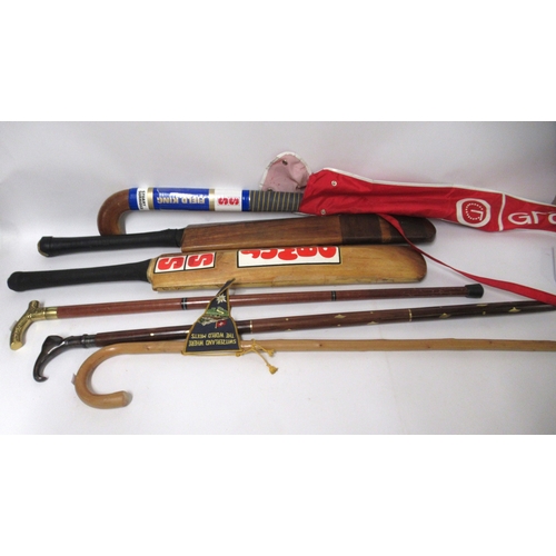 109 - Painted wooden doll's house together with two cricket bats, a hockey stick and three walking canes
