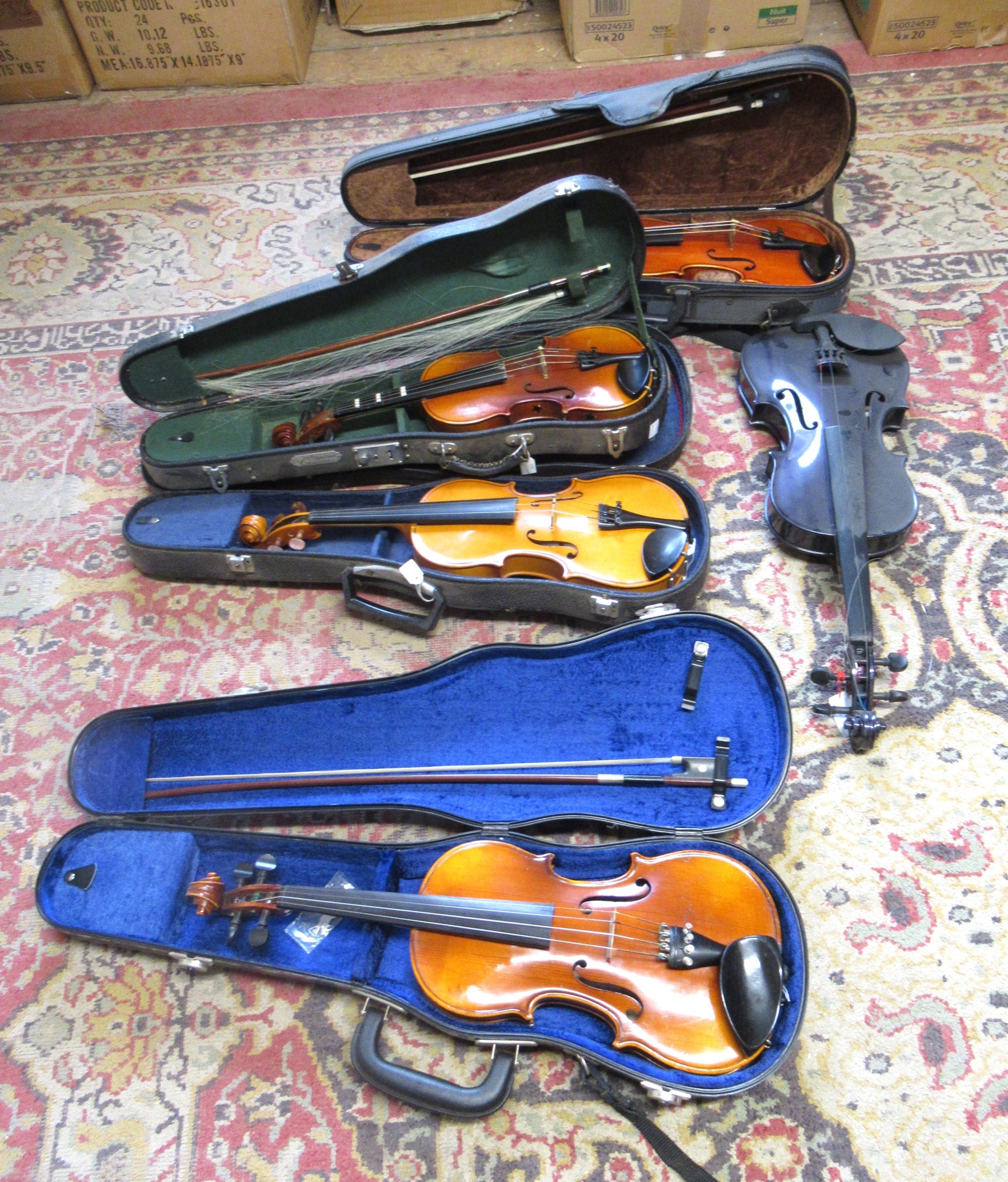 Four cased 20th Century violins and one late 20th Century purple ...
