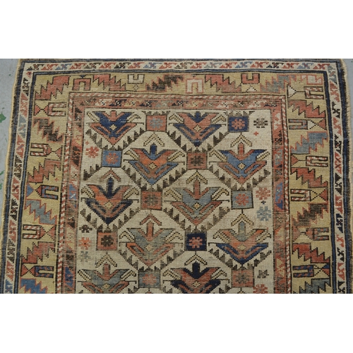 15 - Small Kazak rug with a repeating flower head design on an off-white ground with borders (damages and... 