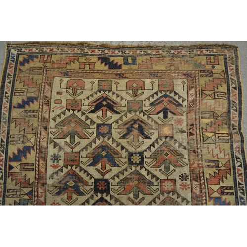 15 - Small Kazak rug with a repeating flower head design on an off-white ground with borders (damages and... 