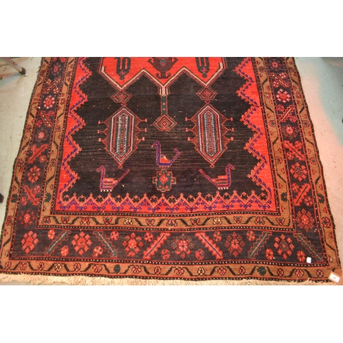 24 - Large Kurdish rug with a geometric red ground centre medallion on a dark ground with further stylise... 
