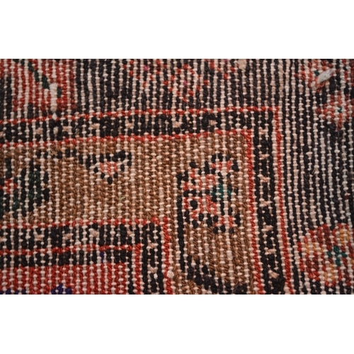24 - Large Kurdish rug with a geometric red ground centre medallion on a dark ground with further stylise... 
