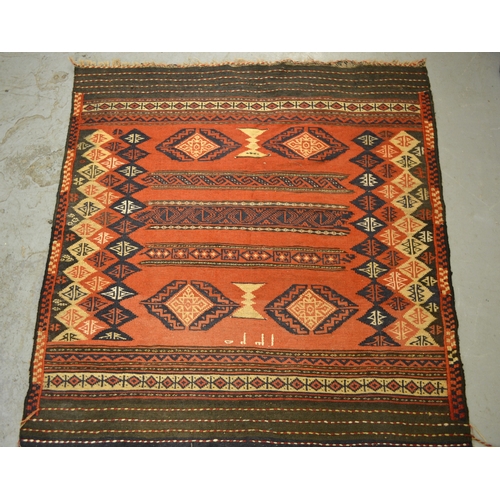 26 - Small Soumak rug with a banded geometric design on a brick red ground with skirt panels, 120 x 115cm... 