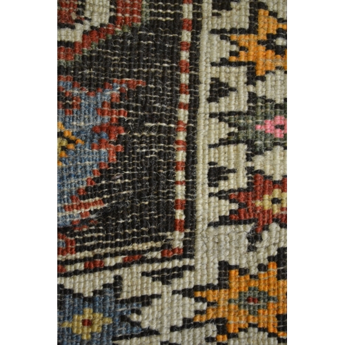 27 - Kazak rug with stylised ram's horn and geometric designs on a brown ground with twin border, 140 x 1... 