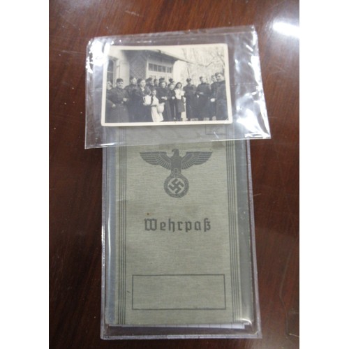 359 - Six German World War II pass books, associated papers and badges