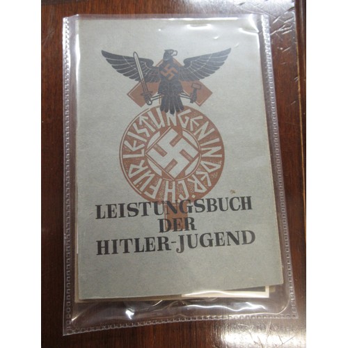 359 - Six German World War II pass books, associated papers and badges