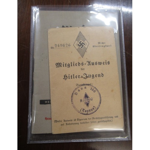 359 - Six German World War II pass books, associated papers and badges