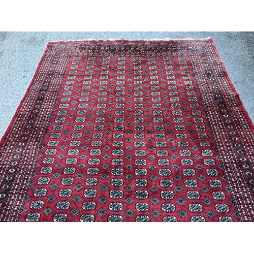 5 - Pakistan Bokhara carpet with eight rows of twenty eight gols on a wine red ground with multiple bord... 