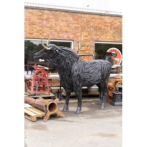 A large bull sculpture crafted from numerous wooden branches. It ...