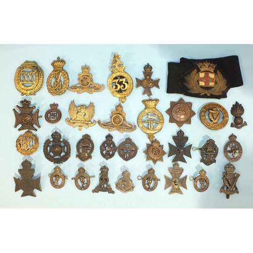 129 - A collection of thirty-two brass and other metal military badges.