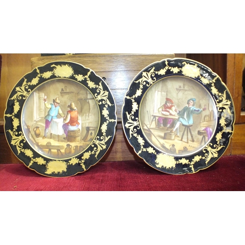 166 - Two continental painted wall plates with blue and gilt surrounds depicting tavern interiors, 23cm di... 