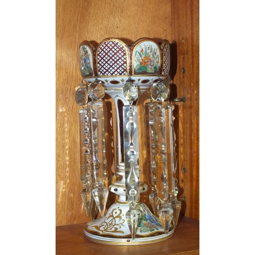 172 - A Victorian overlay cranberry glass lustre decorated with painted floral panels, 29cm high.