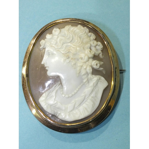 295 - A shell cameo brooch portraying the bust of a young woman with flowers in her hair, in 9ct gold moun... 