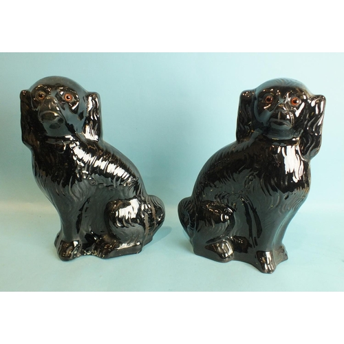 778 - A pair of glazed terracotta black spaniel ornaments, with glass eyes, 34.5cm high.