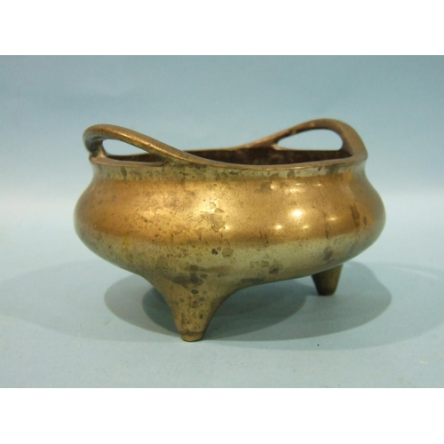 829 - A Chinese bronze metal censer of compressed form, with pierced handles, on three feet, 23cm diameter... 