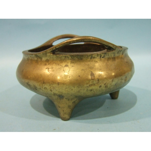 829 - A Chinese bronze metal censer of compressed form, with pierced handles, on three feet, 23cm diameter... 