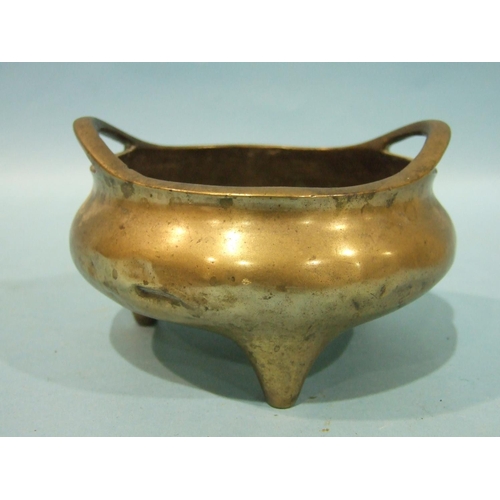 829 - A Chinese bronze metal censer of compressed form, with pierced handles, on three feet, 23cm diameter... 