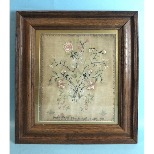 835 - A Victorian needlework silk sampler, depicting a vase of flowers within a flower head and leaf borde... 