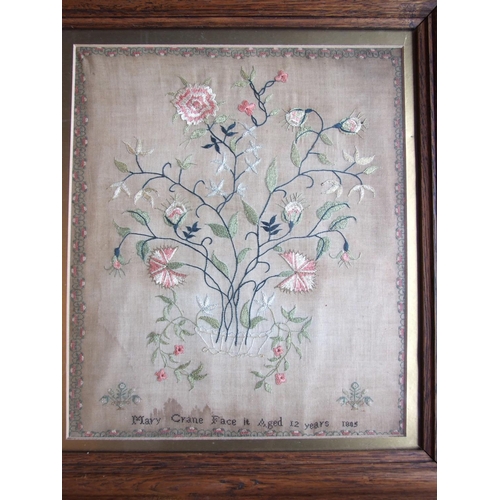 835 - A Victorian needlework silk sampler, depicting a vase of flowers within a flower head and leaf borde... 