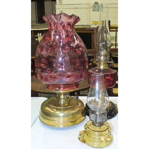 167 - A reproduction oil lamp with cranberry glass reservoir and brass column on ceramic plinth, a modern ... 