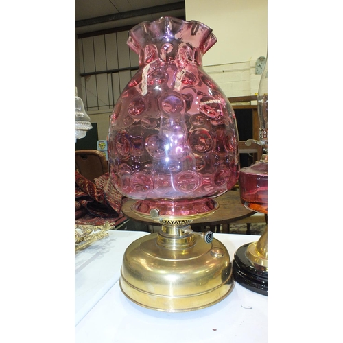 167 - A reproduction oil lamp with cranberry glass reservoir and brass column on ceramic plinth, a modern ... 