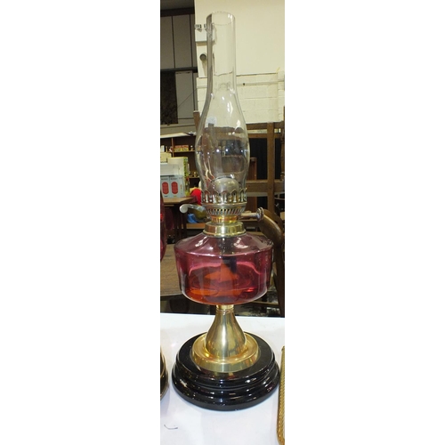 167 - A reproduction oil lamp with cranberry glass reservoir and brass column on ceramic plinth, a modern ... 