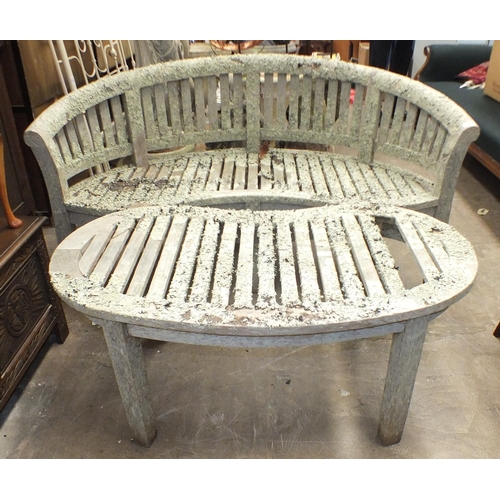 51 - A weathered teak slatted kidney-shaped garden bench, 160cm wide and a matching table, 117 x 56cm.... 