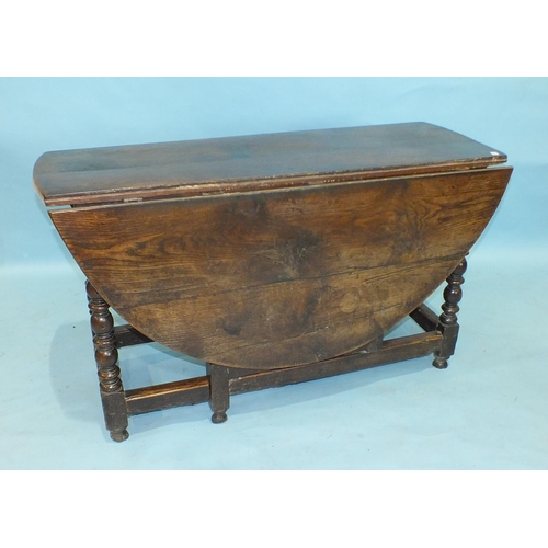 53 - An antique oak drop-leaf dining table, the oval top above an end frieze drawer, on bobbin-turned leg... 