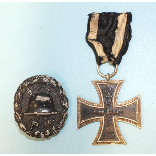 164 - A German WWI Iron Cross and a black wound badge, (2).