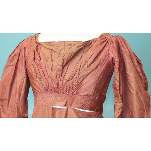 524 - An early-19th century puce silk dress, hand-stitched, the bodice gathered at the front and on the sh... 