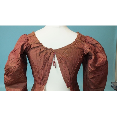 524 - An early-19th century puce silk dress, hand-stitched, the bodice gathered at the front and on the sh... 