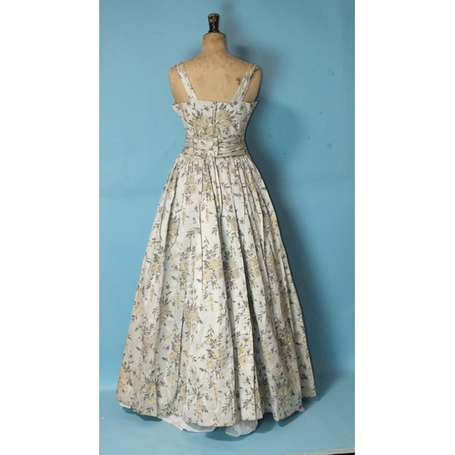 530 - A 1950's ivory floral brocade evening dress, sleeveless, with full pleated skirt and bow waist band,... 