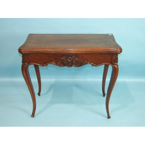 103 - A 19th century mahogany fold-over card table, the serpentine top with carved frieze and carved cabri... 