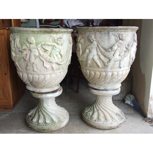 121 - A pair of large cast concrete garden-urns decorated with frolicking cherubs, 56cm diameter, 90cm hig... 