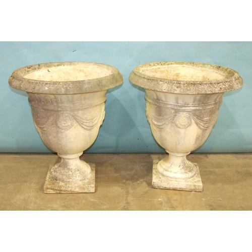 122 - A pair of cast concrete bell shape garden urns decorated with drapery, 61cm diameter, 68cm high.... 