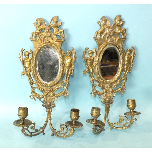 166 - A pair of cast brass and mirrored girandoles decorated with cherubs and ribbon-tied husks, 34cm high... 