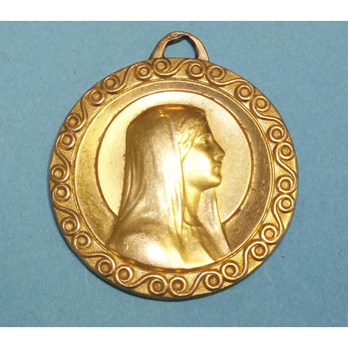 281 - A yellow metal circular pendant with raised head and shoulders of the Virgin Mary within scrolling b... 