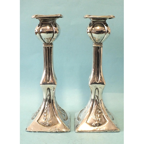 541 - A pair of Art Nouveau-style loaded candlesticks of square form, each base embossed with lilies of th... 