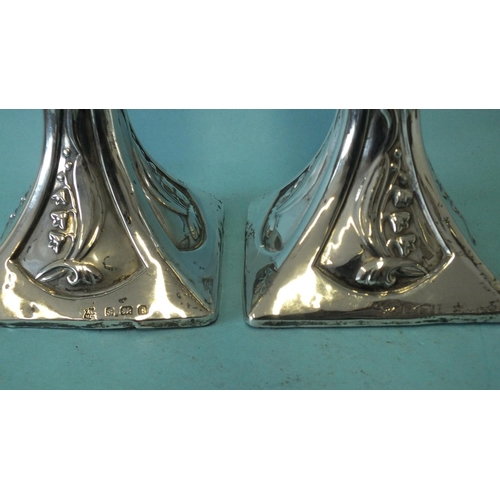 541 - A pair of Art Nouveau-style loaded candlesticks of square form, each base embossed with lilies of th... 