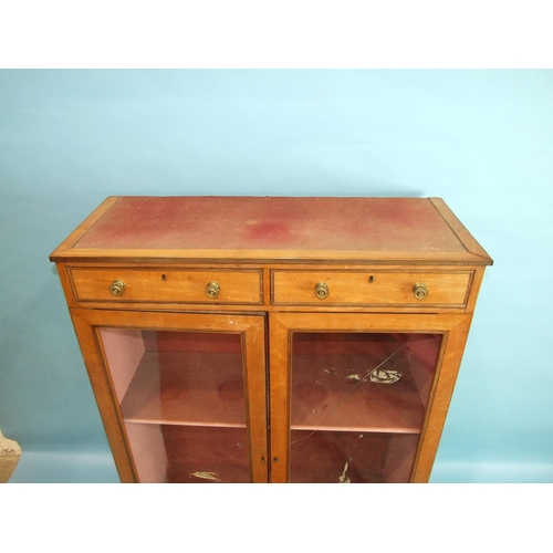 80 - A 19th century satinwood bookcase, having a pair of small drawers above two glazed doors, on square ... 