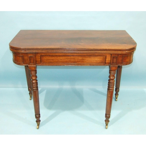 89 - A George IV mahogany fold-over card table, having a concealed frieze drawer on ring-turned legs with... 