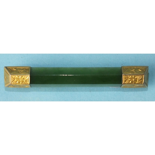 333 - A nephrite bar brooch with engraved gold terminals, 6cm long, 6.7g.