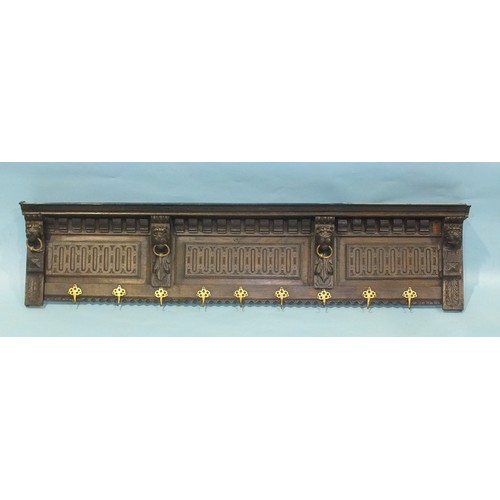 97 - An antique oak cornice with carved and dentil detail, with lion corbels holding brass rings, now wit... 