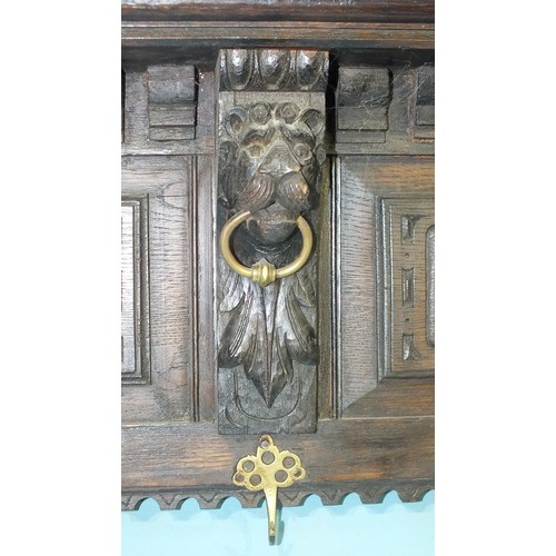 97 - An antique oak cornice with carved and dentil detail, with lion corbels holding brass rings, now wit... 