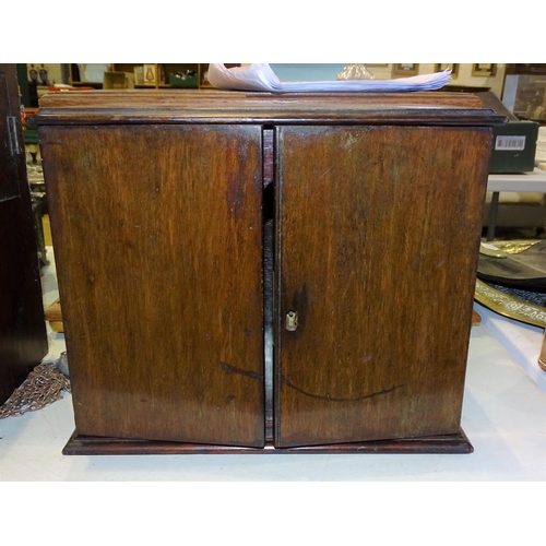 100 - A mahogany smoker's cabinet fitted with two doors opening to reveal two drawers and a pipe rack, 31c... 