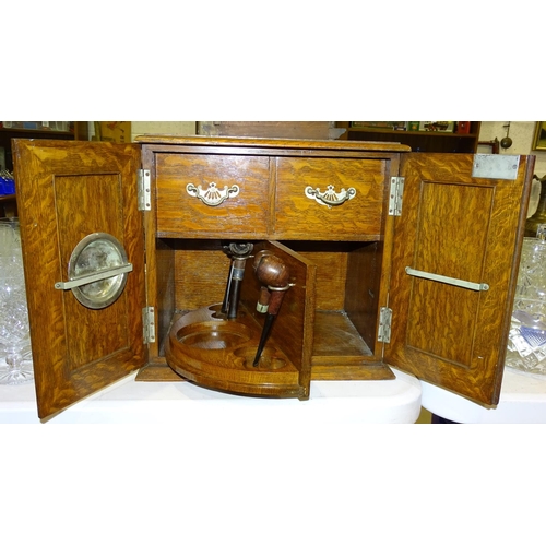 118 - An oak smoker's cabinet fitted with a pair of doors opening to reveal two drawers and a revolving pi... 